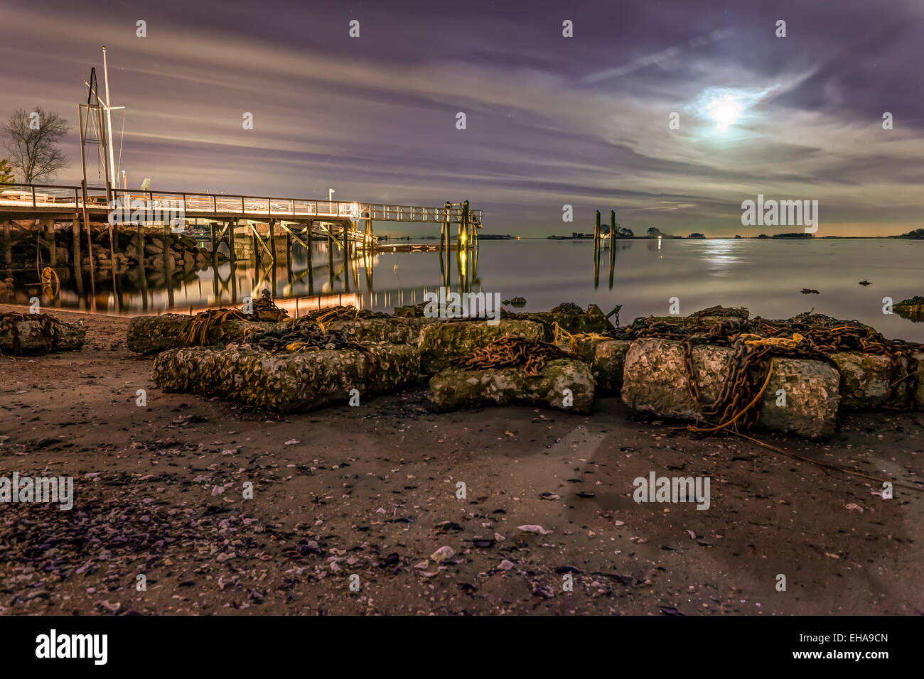 De grandes dalles de ciment avec les chaînes sur la rive par un quai sous purple sky. Banque D'Images