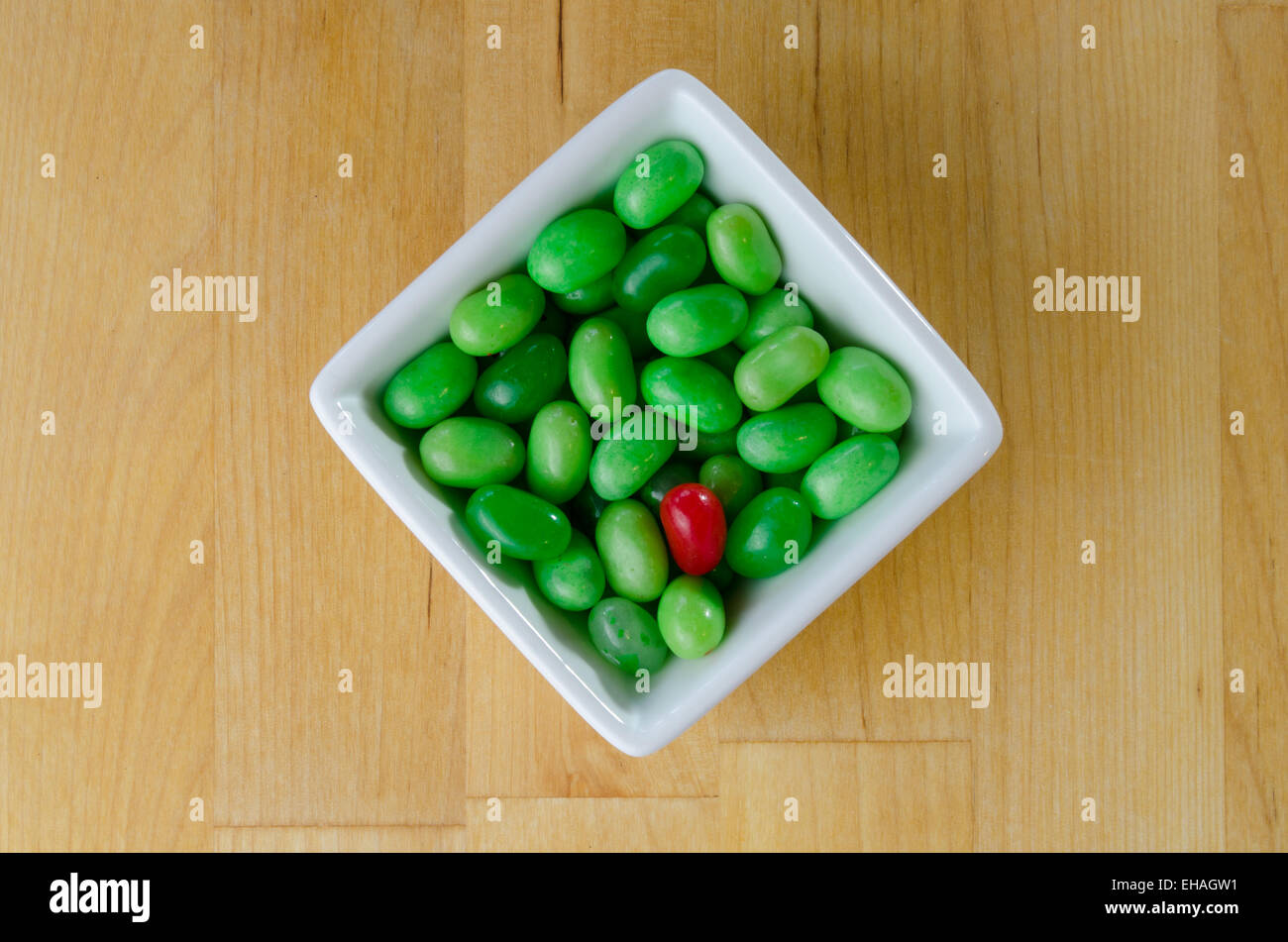 Un seul red jelly bean se détache sur un tas de bonbons haricots verts Banque D'Images