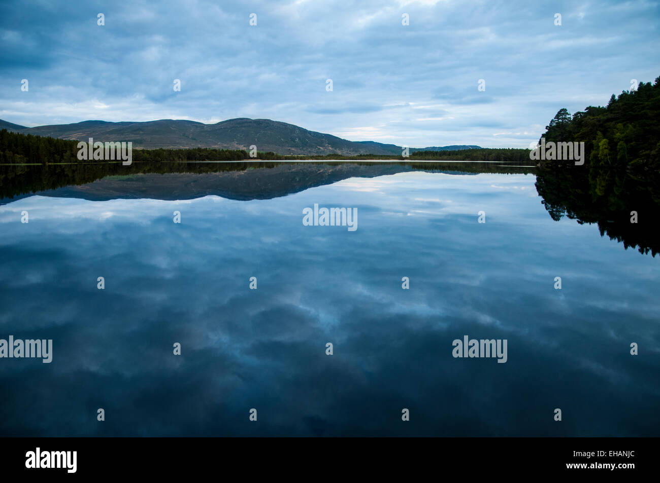 Un ciel nuageux au crépuscule reflète dans les eaux calmes du Loch Garten, Inverness-shire. Mai. Banque D'Images