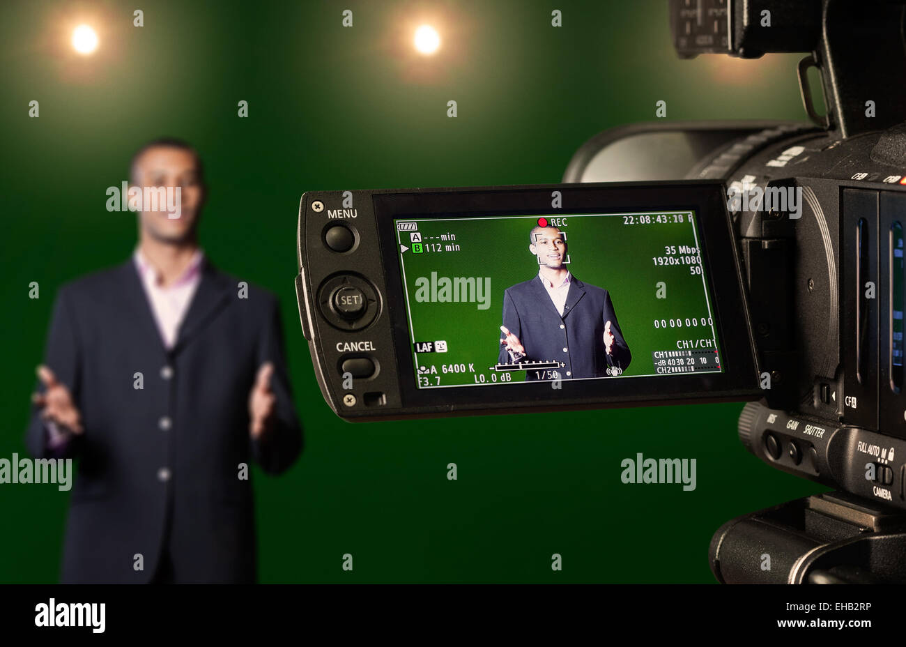 Présentateur de télévision dans un studio de télévision écran vert, vu à travers l'écran LCD d'un appareil photo numérique. Focus sélectif. Banque D'Images