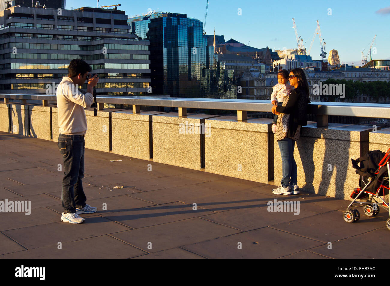 Un homme de prendre une photo de sa femme et son enfant sur le pont de Londres au coucher du soleil Banque D'Images