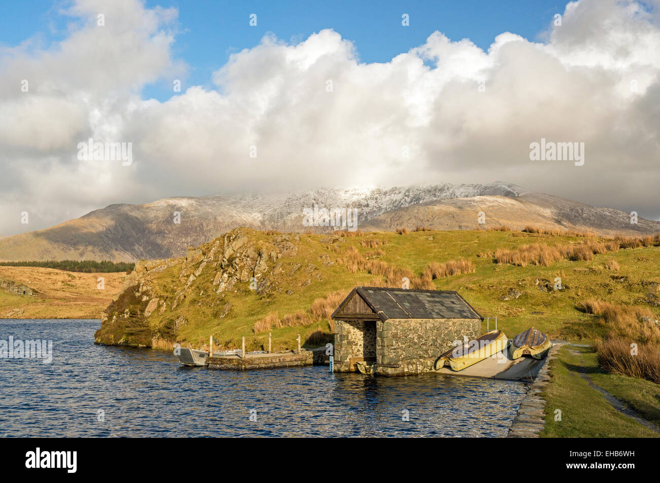 Llyn y Dywarchen Lake et de hangars à bateaux dans le parc national de Snowdonia avec Snowdon derrière plafonnés par cloud, Nord du Pays de Galles UK Banque D'Images