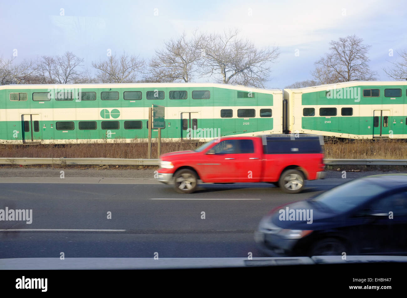 Un train de voyageurs à double étage canadien voyageant parallèle à une autoroute. Banque D'Images