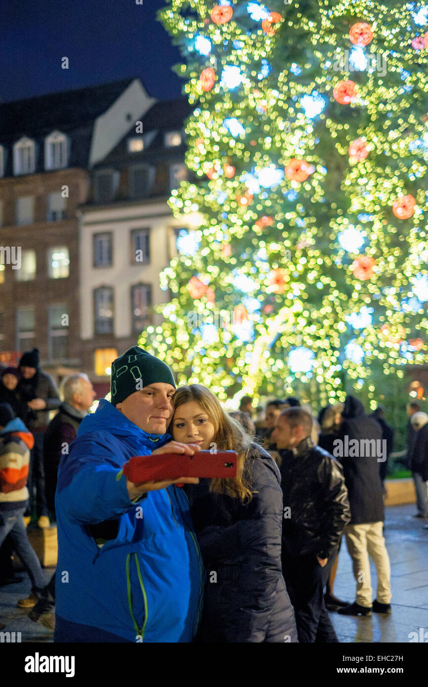 Couple qui photographie selfies en face de l'arbre de Noël illuminé géant, Place Kléber, place de Strasbourg Alsace France Europe Banque D'Images