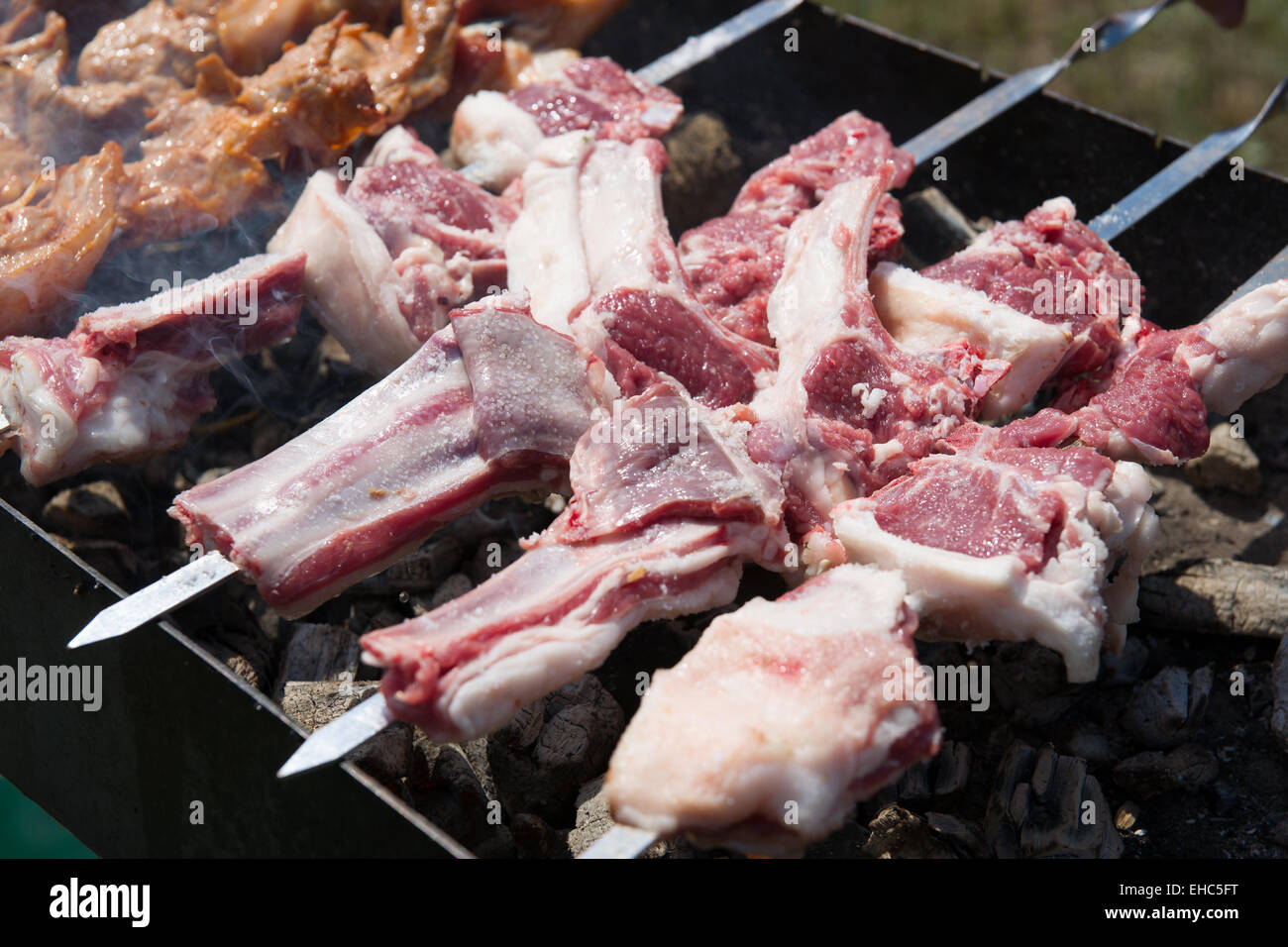 Préparation d'agneau grillées traditionnelle connue sous le nom de shish kebab ou des brochettes. La viande, la fumée et le charbon de la chaleur. Banque D'Images