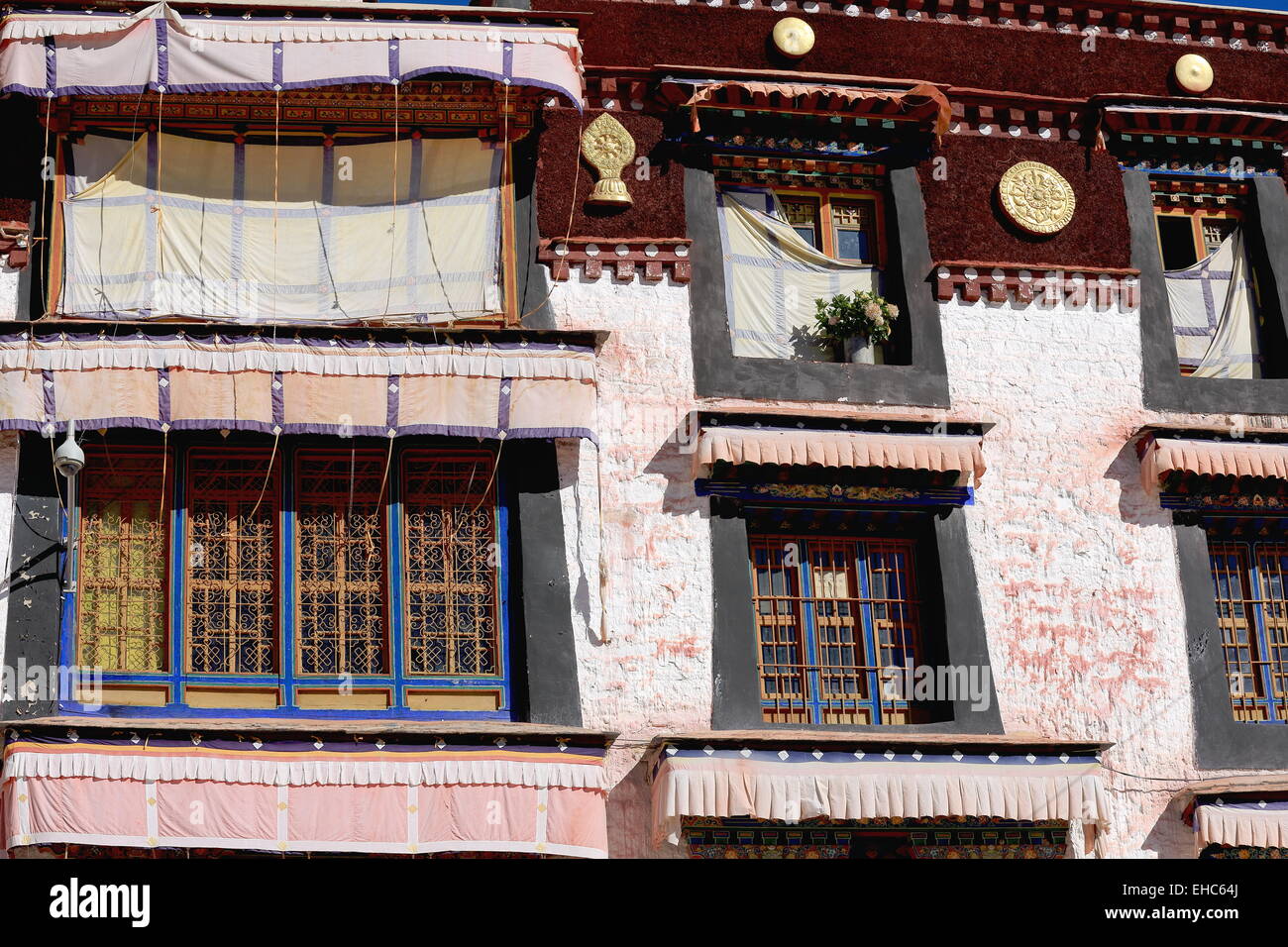 Fenêtres en bois sur le coloriste des murs blancs de la heap Drepung-Rice Gelugpa-Yellow monastère bouddhiste de la Hat l'école. Banque D'Images