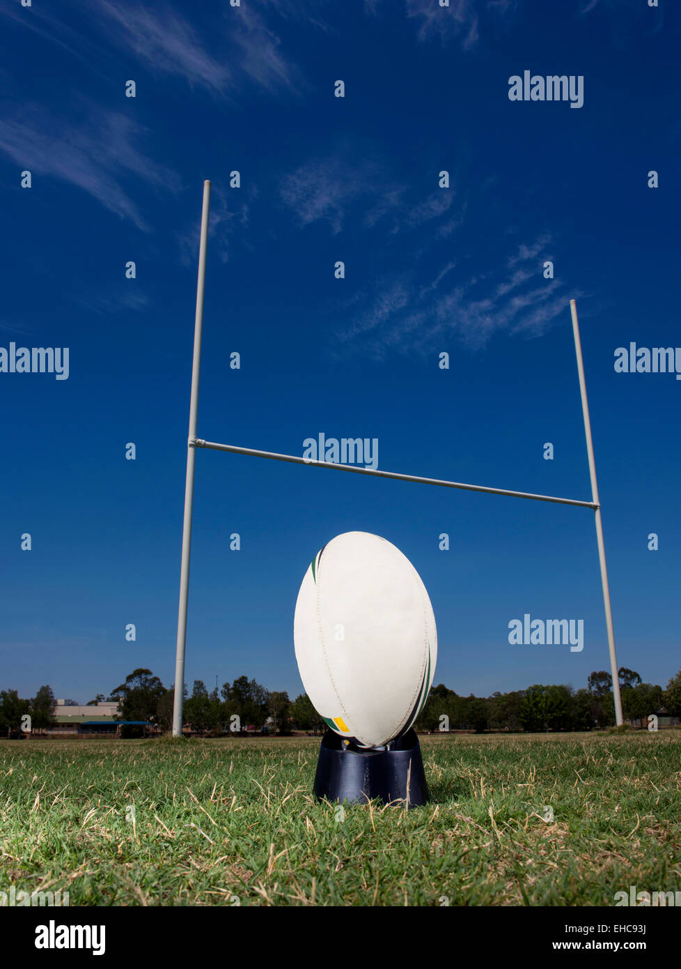 Ballon de rugby est assis sur un tee, prêt à être frappé par les poteaux de but, avec un ciel bleu en arrière-plan. Banque D'Images