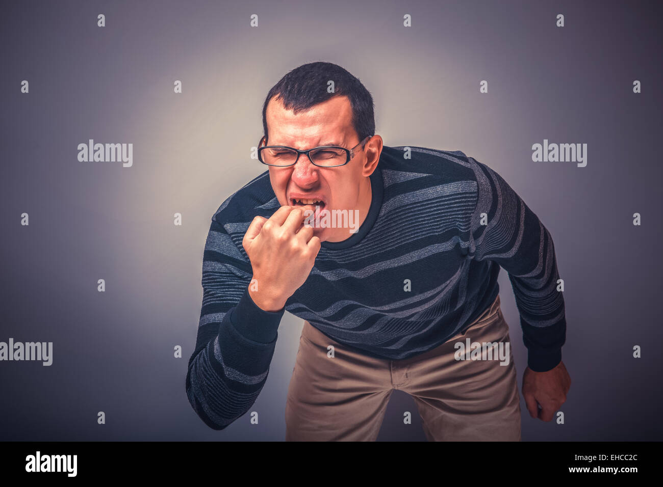 Homme d'apparence brunet mettre ses doigts dans sa bouche Banque D'Images