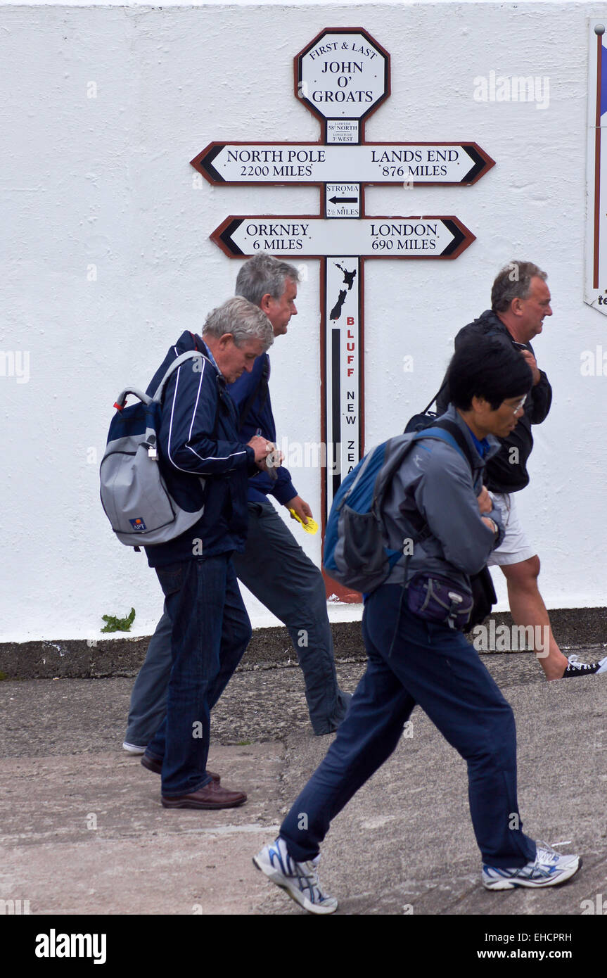 Les promeneurs passant l'enseigne l'affichage des distances à Land's End, John O'Groats, Caithness, Ecosse Banque D'Images