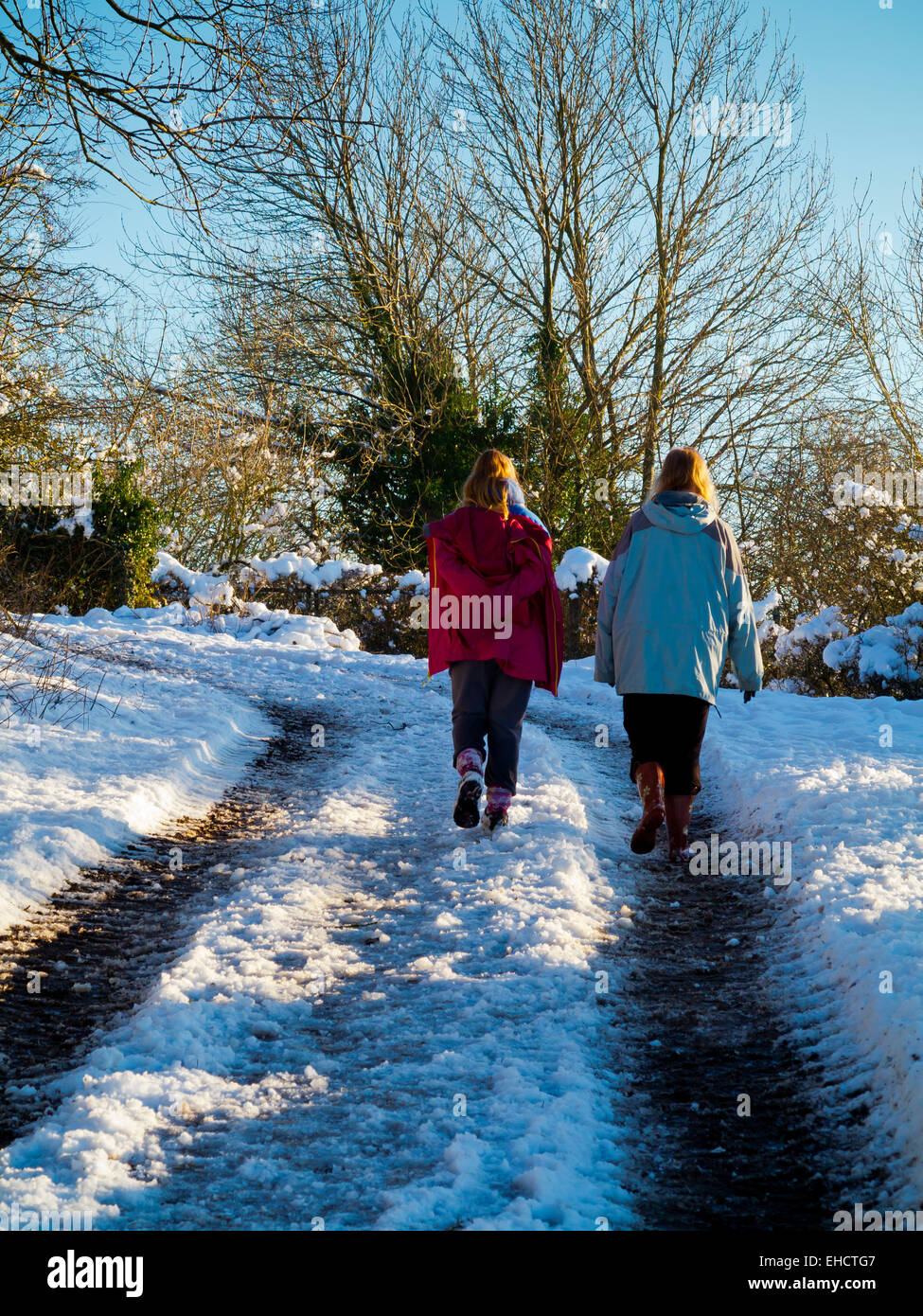 Femme et enfant marche sur un chemin couvert de neige près de Matlock dans le Peak District Derbyshire Dales England UK Banque D'Images