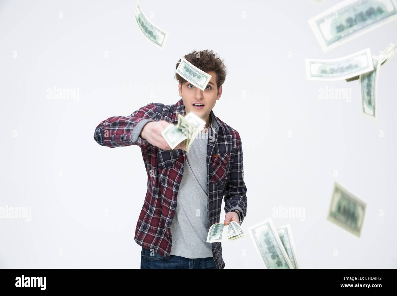 Jeune homme séduisant en jetant de l'argent en l'air sur fond gris Banque D'Images