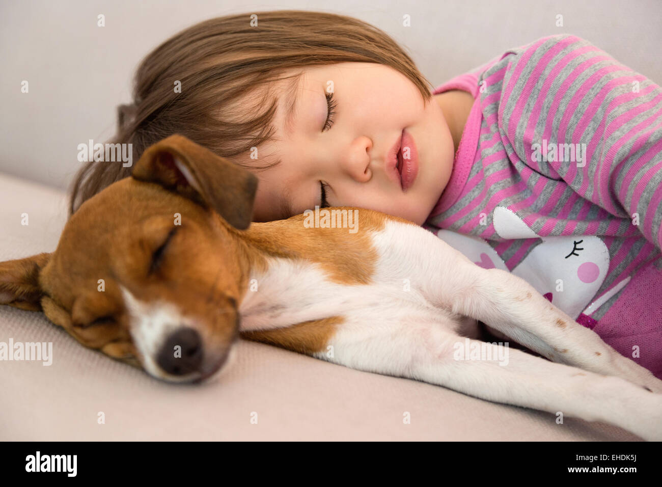 Bébé fille dormir à côté de mixed breed puppy dog Banque D'Images