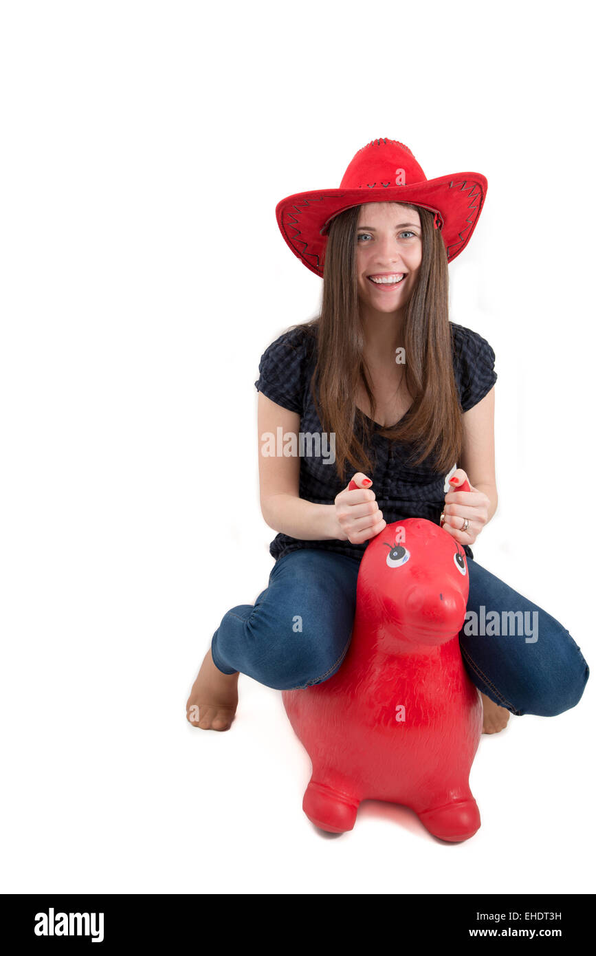 Jeune fille avec chapeau de cow-boy rouge équitation o cheval jouet isolated Banque D'Images