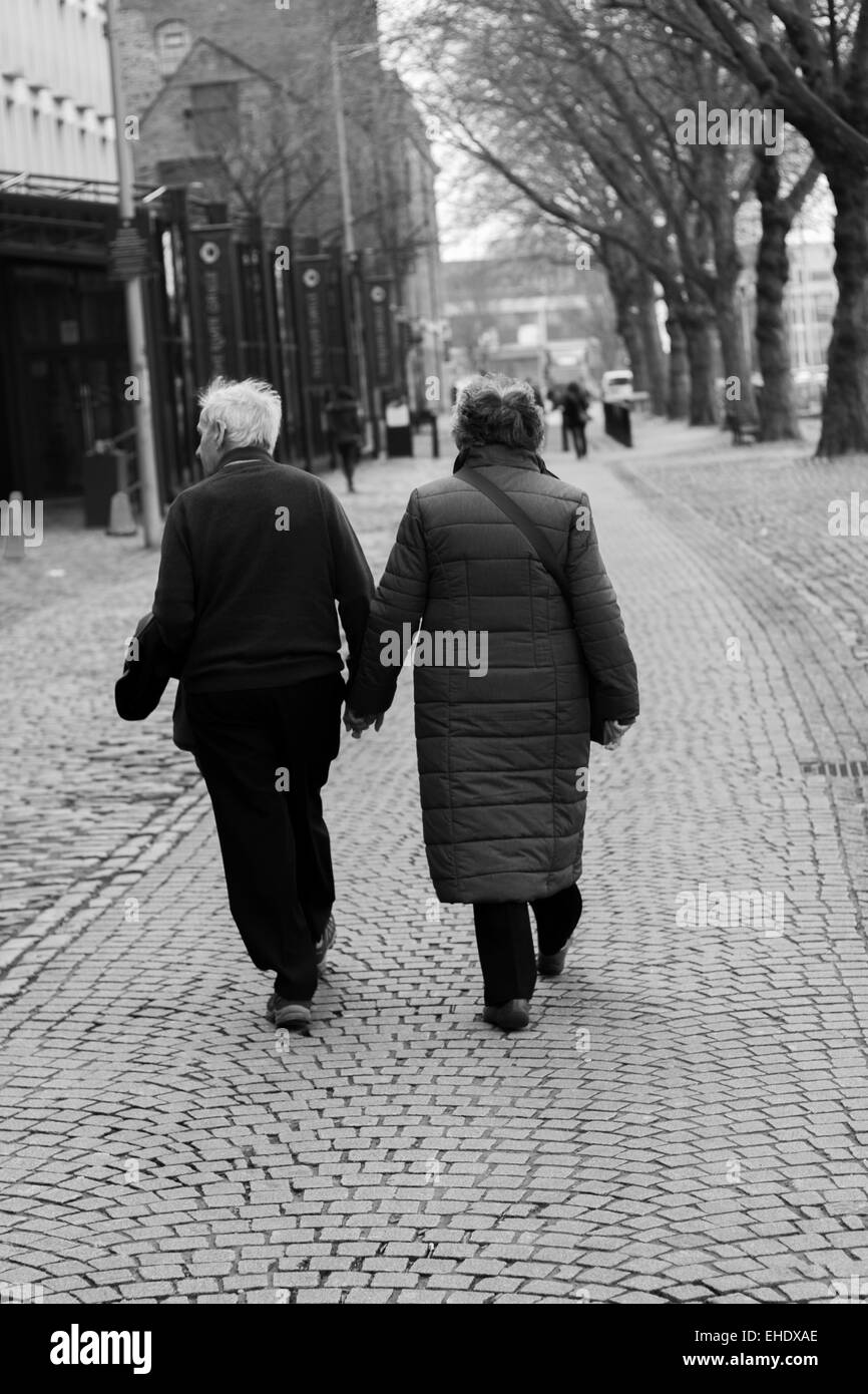 Vieux couple marche main dans la main, rue pavées Banque D'Images