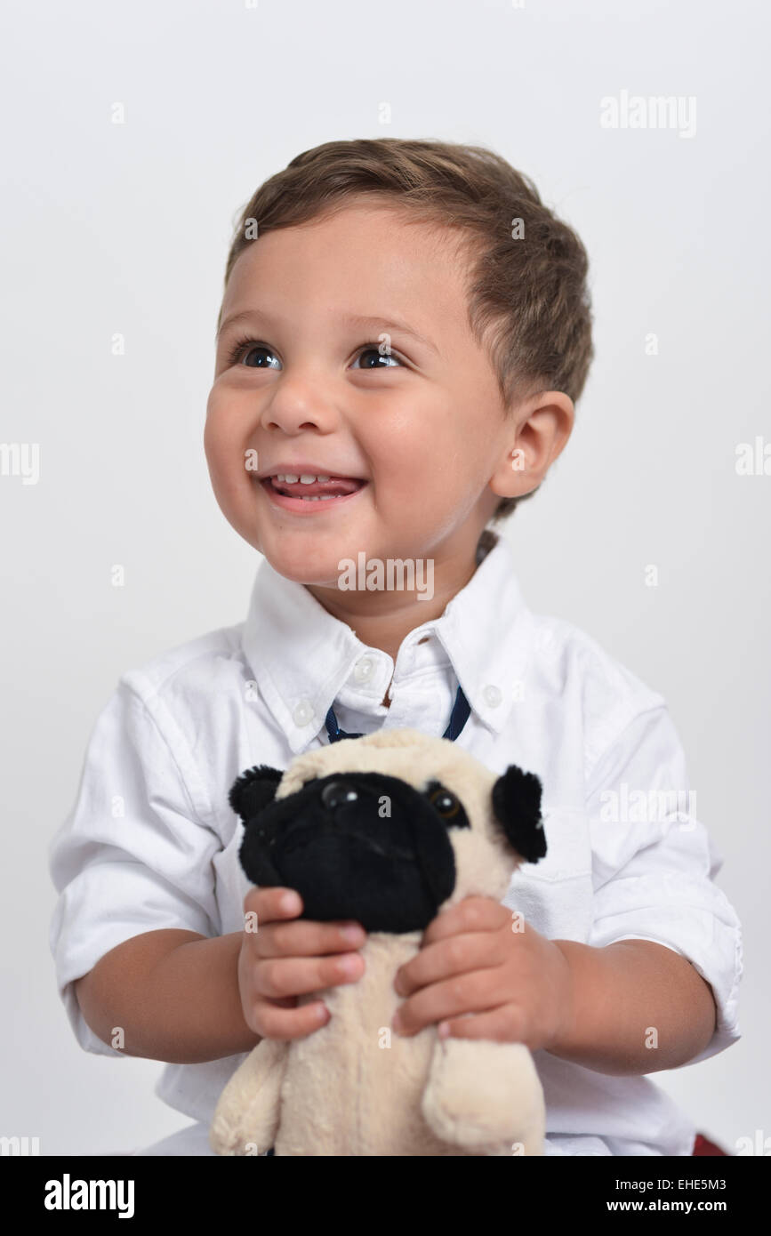 Deux ans cute boy tient une fleur et un animal en peluche posant isolé dans un fond blanc. Banque D'Images