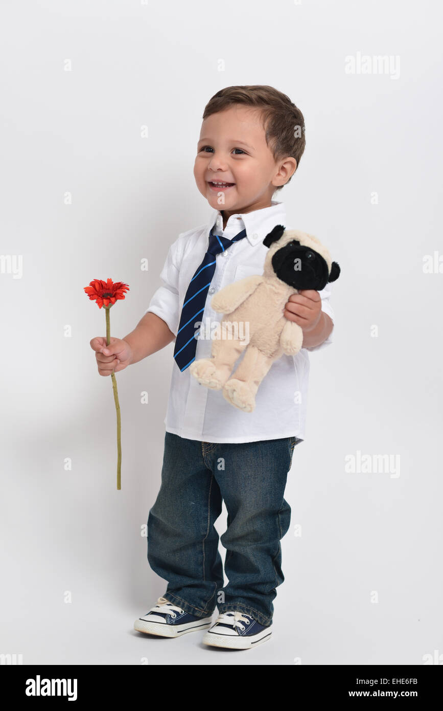 Deux ans adorable enfant tenant une fleur et un animal en peluche - isolé sur un fond blanc. Banque D'Images