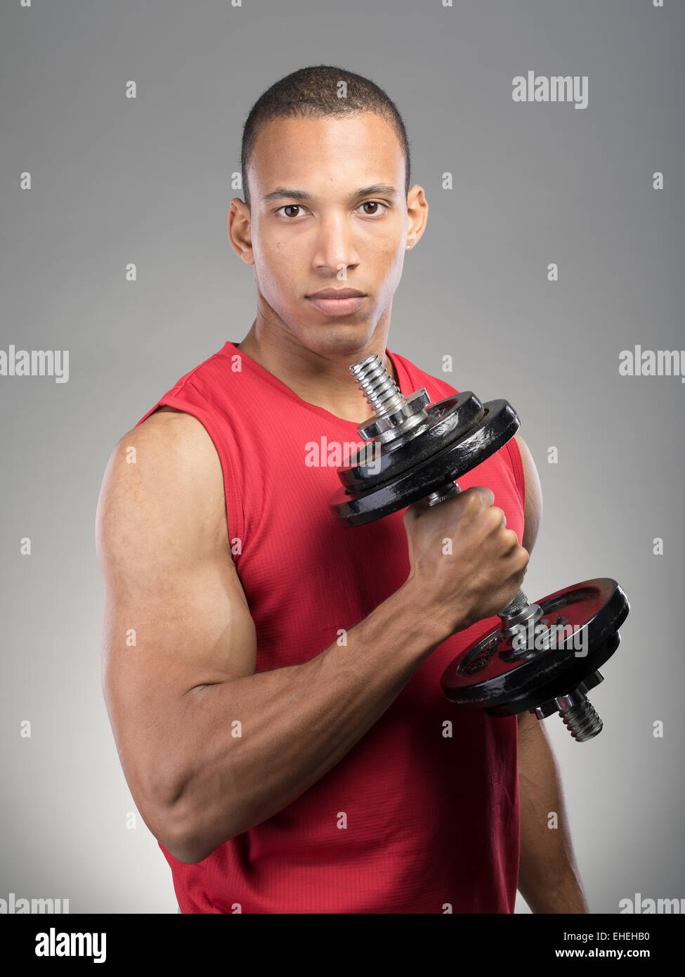 Muscular man wearing red tank top vest en utilisant barbell Banque D'Images