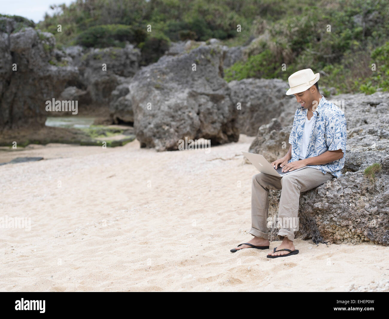 L'homme à l'aide d'Apple Macbook Air ordinateur portable ordinateur portable pour travailler sur la plage pendant les vacances Banque D'Images