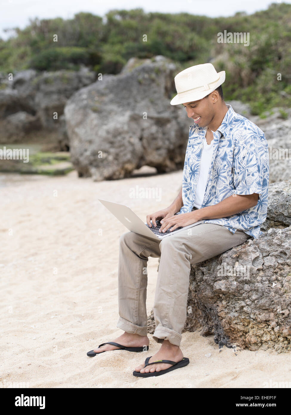 L'homme à l'aide d'Apple Macbook Air ordinateur portable ordinateur portable pour travailler sur la plage pendant les vacances Banque D'Images