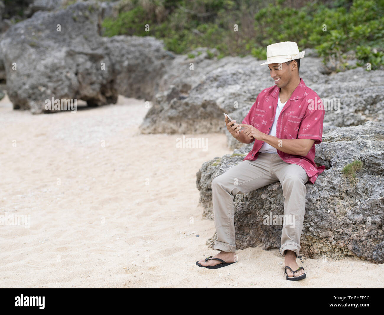 Man texting / contrôle internet sur smartphone Apple iphone 6 alors qu'à la plage Banque D'Images