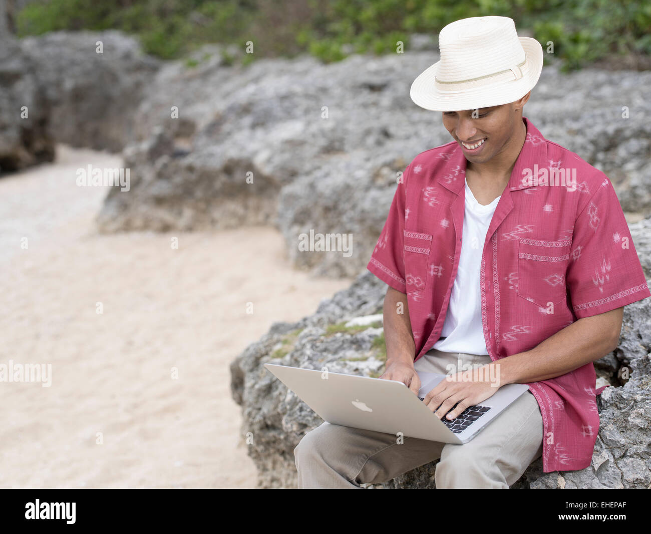 L'homme à l'aide d'Apple Macbook Air ordinateur portable ordinateur portable pour travailler sur la plage pendant les vacances Banque D'Images