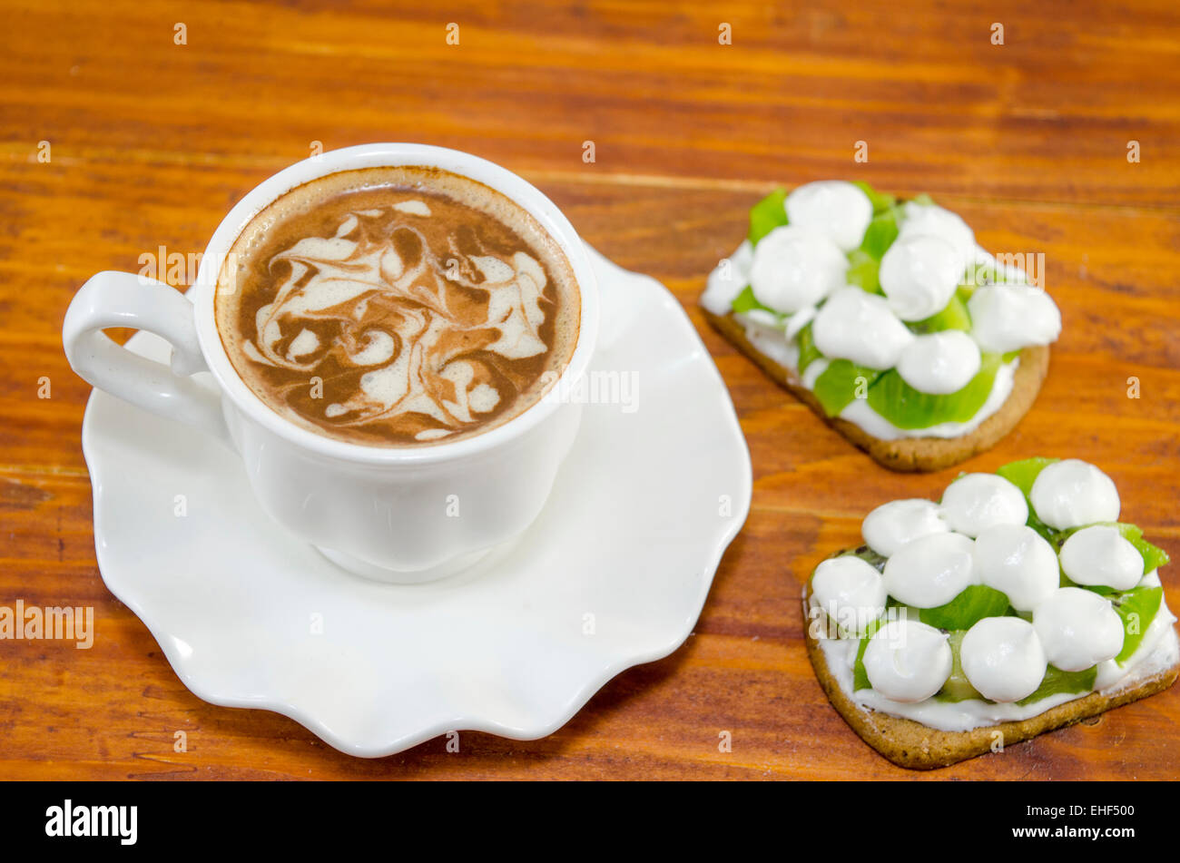 Tasse de café avec de la mousse et décoré avec des biscuits à la crème de kiwi Banque D'Images