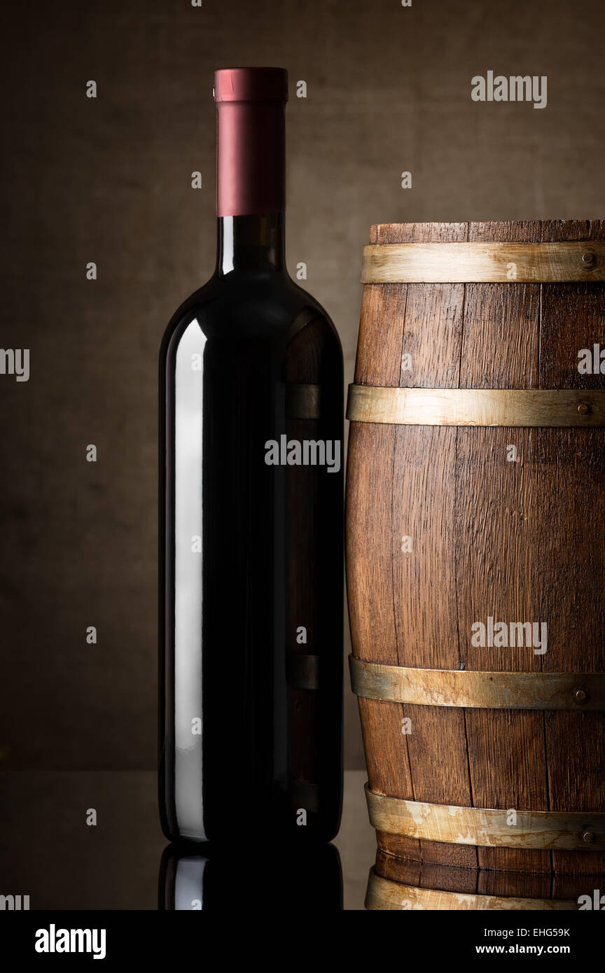 Vin rouge dans une bouteille près de tonneau en bois Banque D'Images