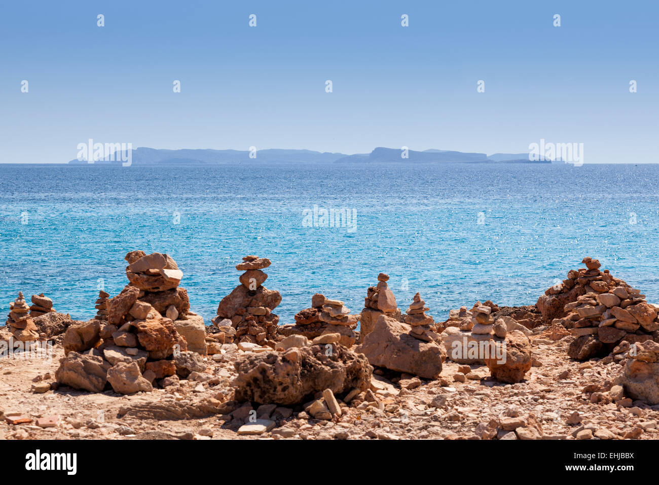 Zen Stone stacks sur plage de galets en face d'une île Banque D'Images