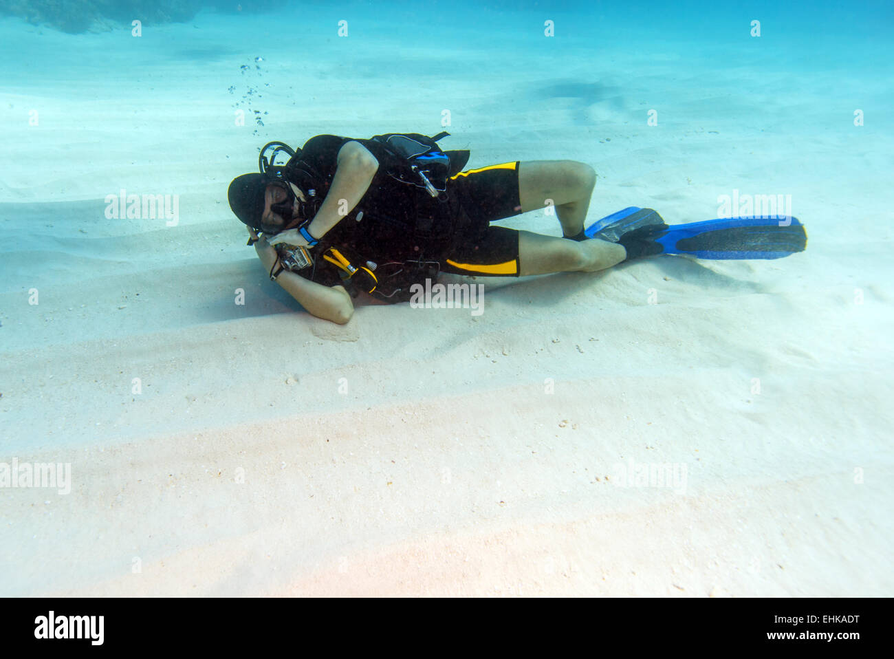Plongeur homme dormir sur fond de mer de sable Banque D'Images