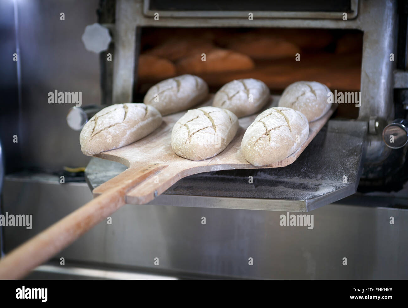 Baker plaçant miches de pain dans le four Banque D'Images