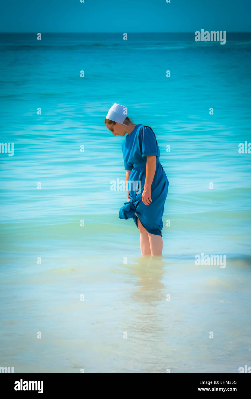Amish une dame, habillée de manière traditionnelle de la pagaie dans les eaux de surf à Siesta Key Beach à Sarasota, FL Banque D'Images
