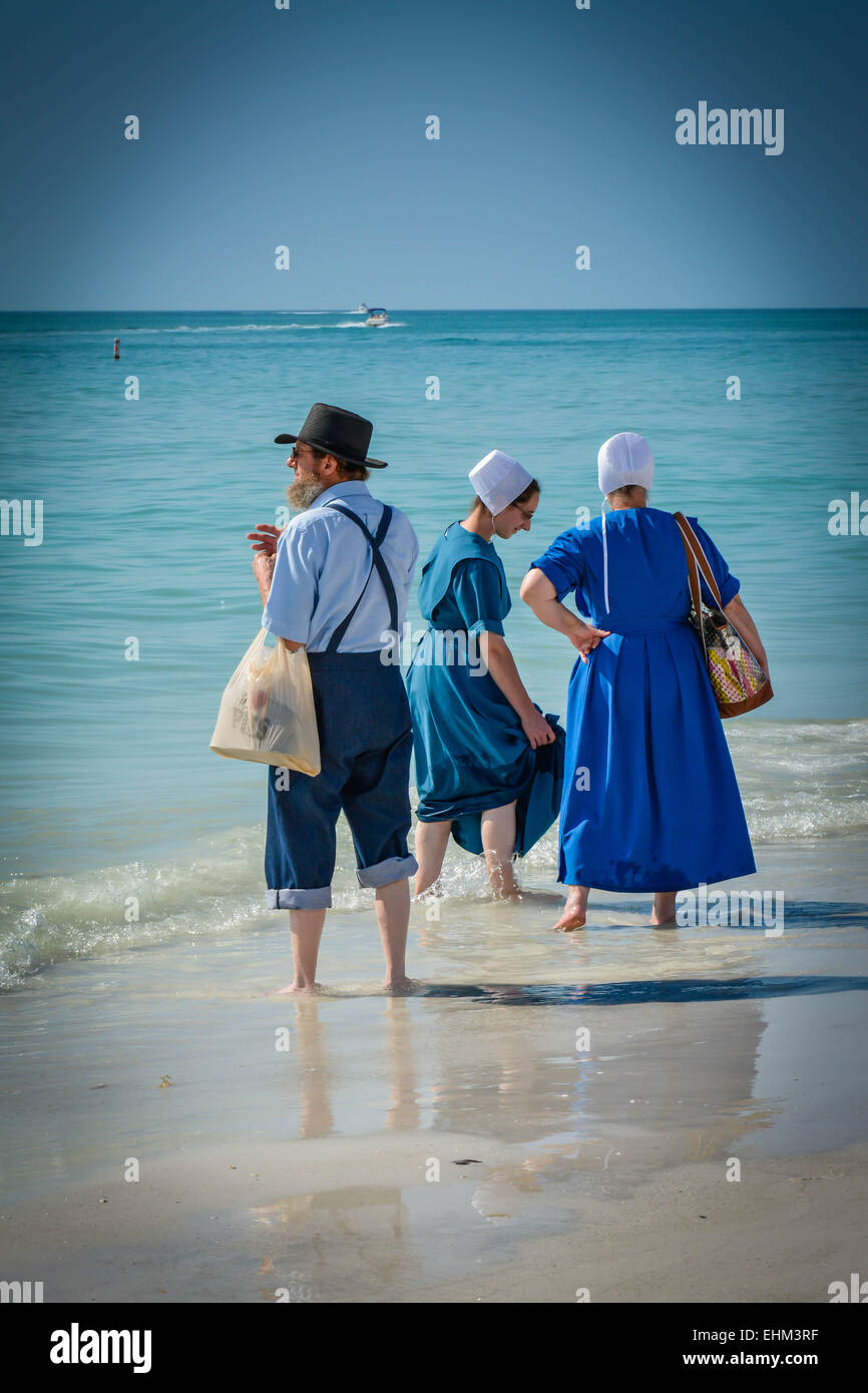 Trois Amish, vêtus de leurs vêtements traditionnels, pagayez dans les vagues peu profondes de Siesta Key Beach à Sarasota, en Floride Banque D'Images