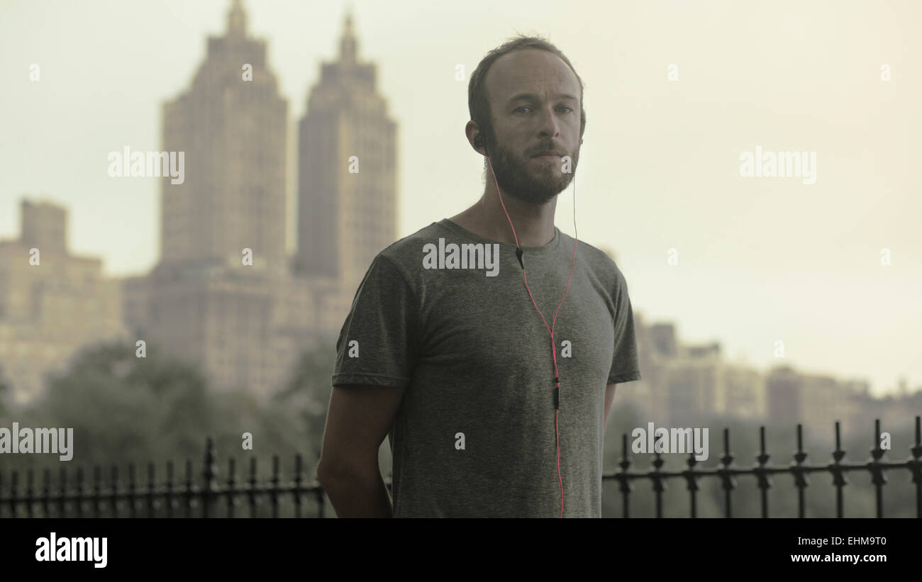 Caucasian runner à écouter les écouteurs en face de city skyline Banque D'Images