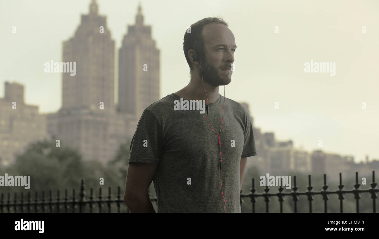Caucasian runner à écouter les écouteurs en face de city skyline Banque D'Images