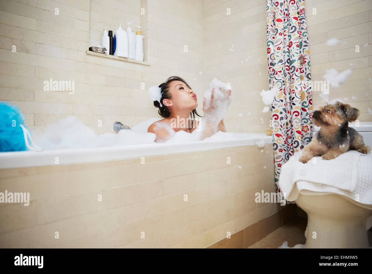 Chinese Woman Playing with dog in bubble bath Banque D'Images