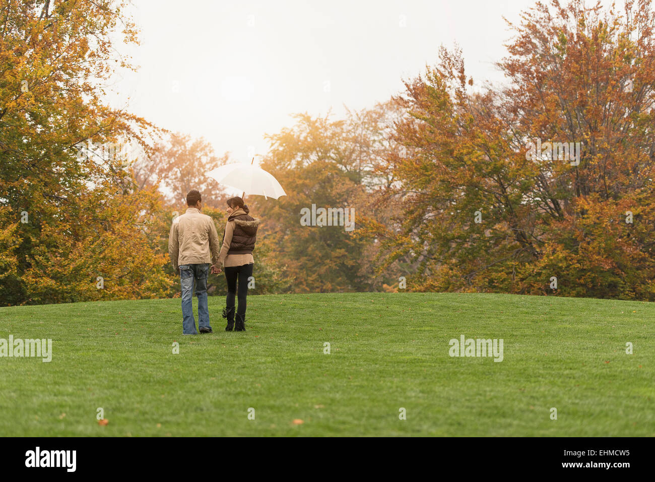 Couple walking with umbrella in park Banque D'Images