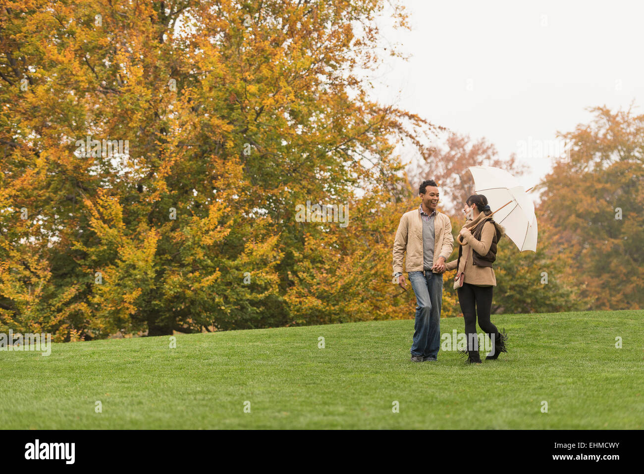 Couple walking with umbrella in park Banque D'Images