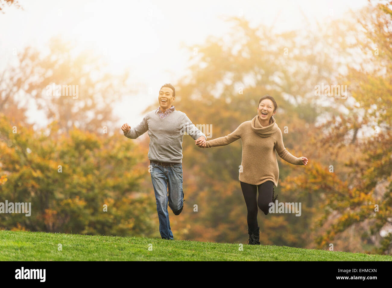 Smiling couple running in park Banque D'Images