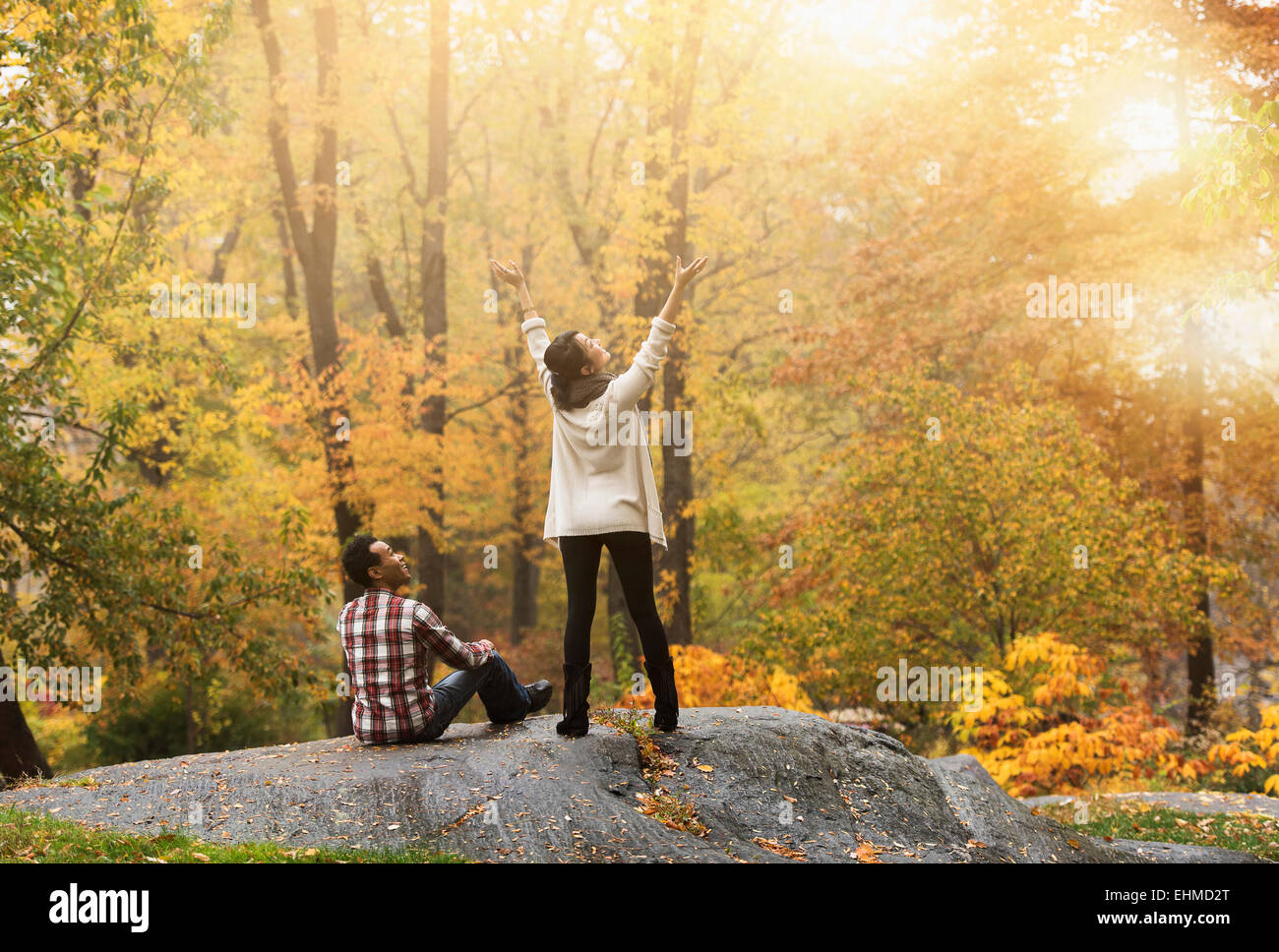 Woman cheering with arms outstretched près de petit ami en park Banque D'Images