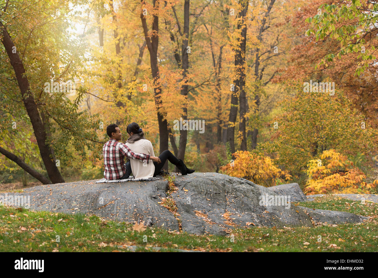 Asian couple hugging on rock in park Banque D'Images