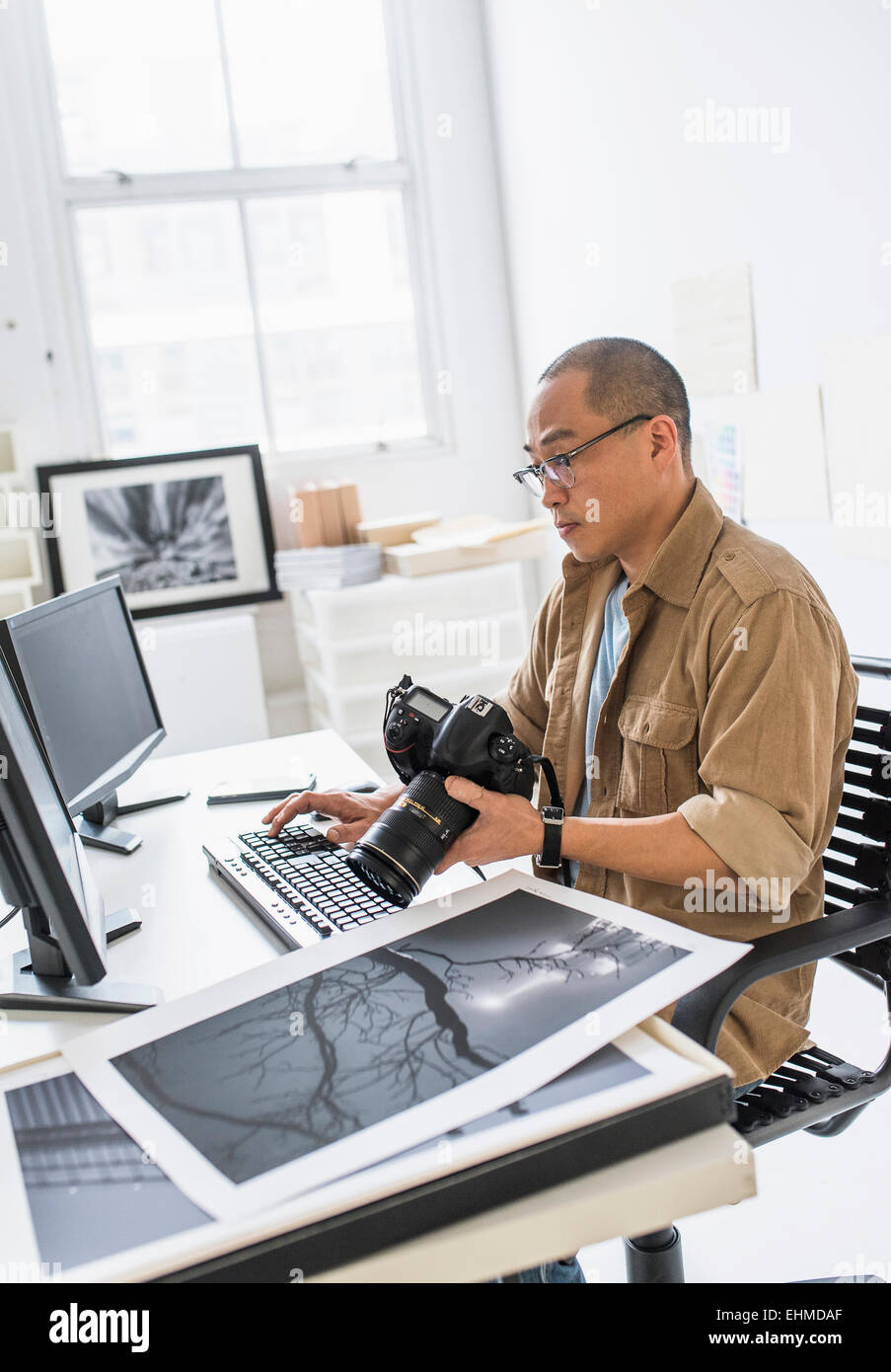 Photographe coréen à l'aide d'ordinateur au bureau Banque D'Images