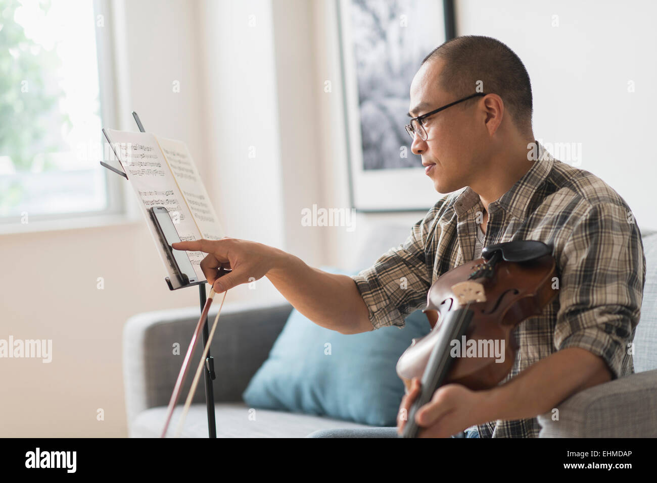 Musicien coréen using cell phone in living room Banque D'Images