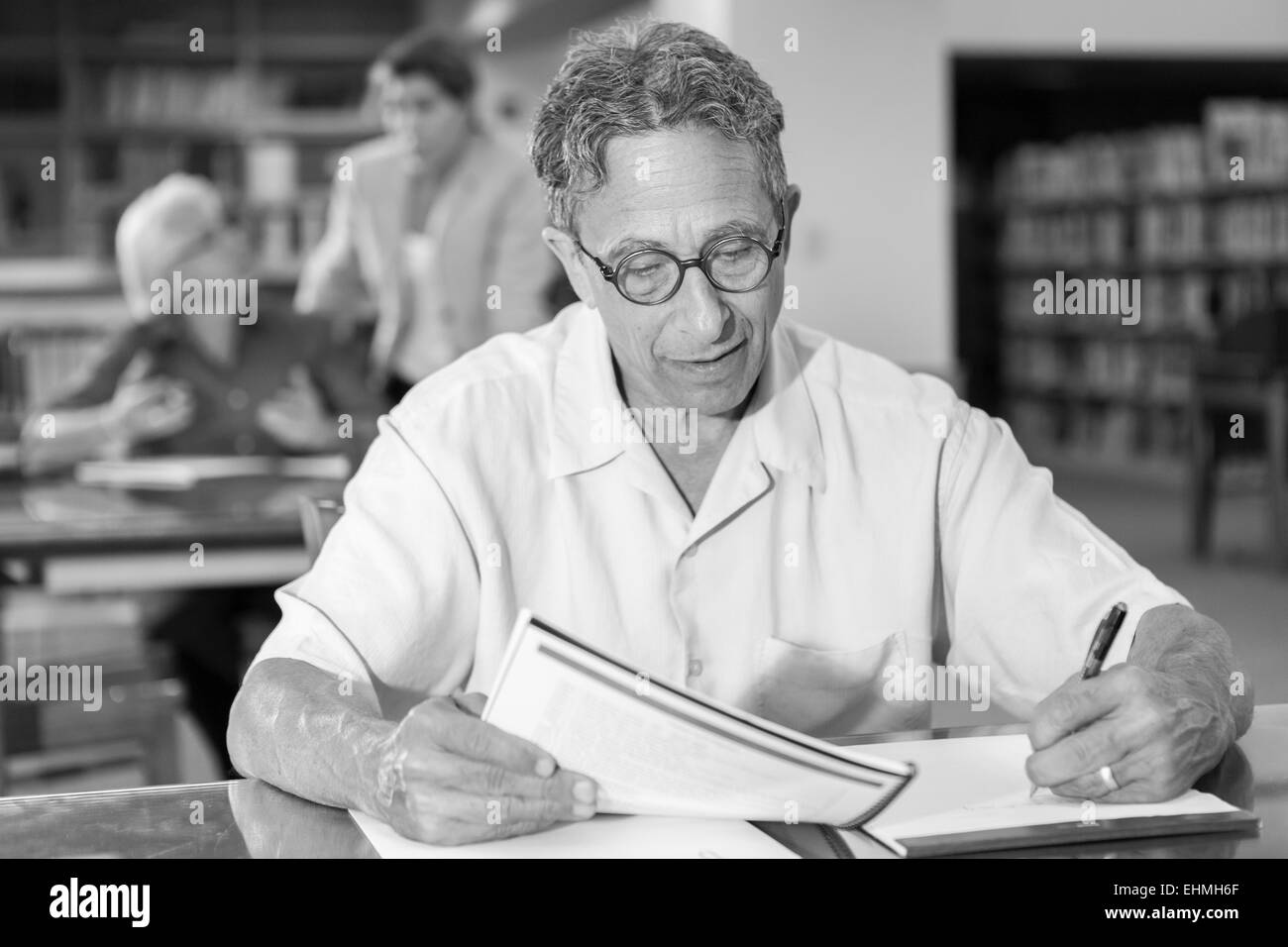 Man writing on notepad in library Banque D'Images