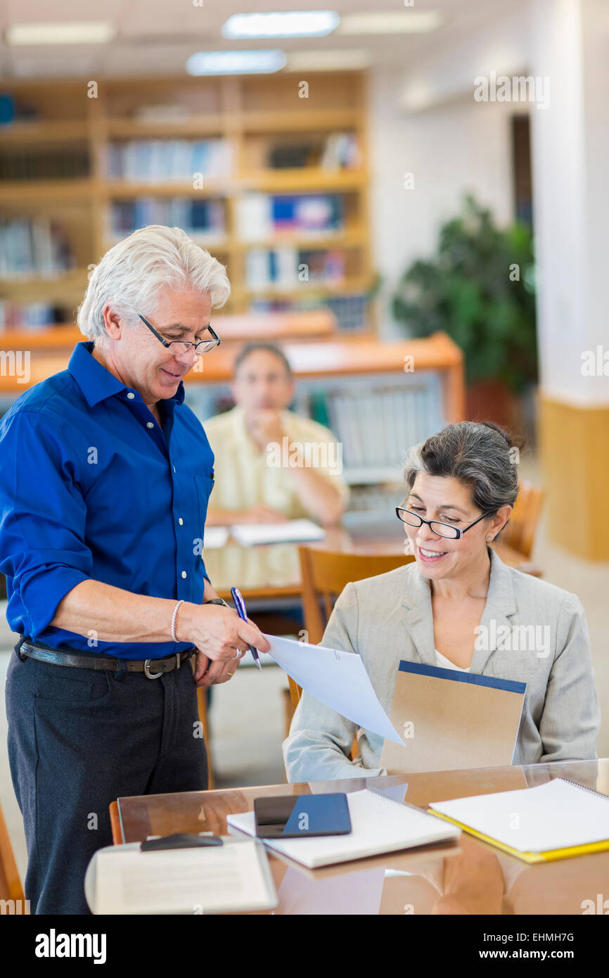 Aider les enseignants les étudiants adultes d'utiliser digital tablet in library Banque D'Images