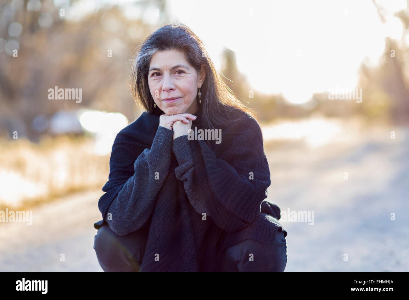 Plus Hispanic woman crouching outdoors Banque D'Images