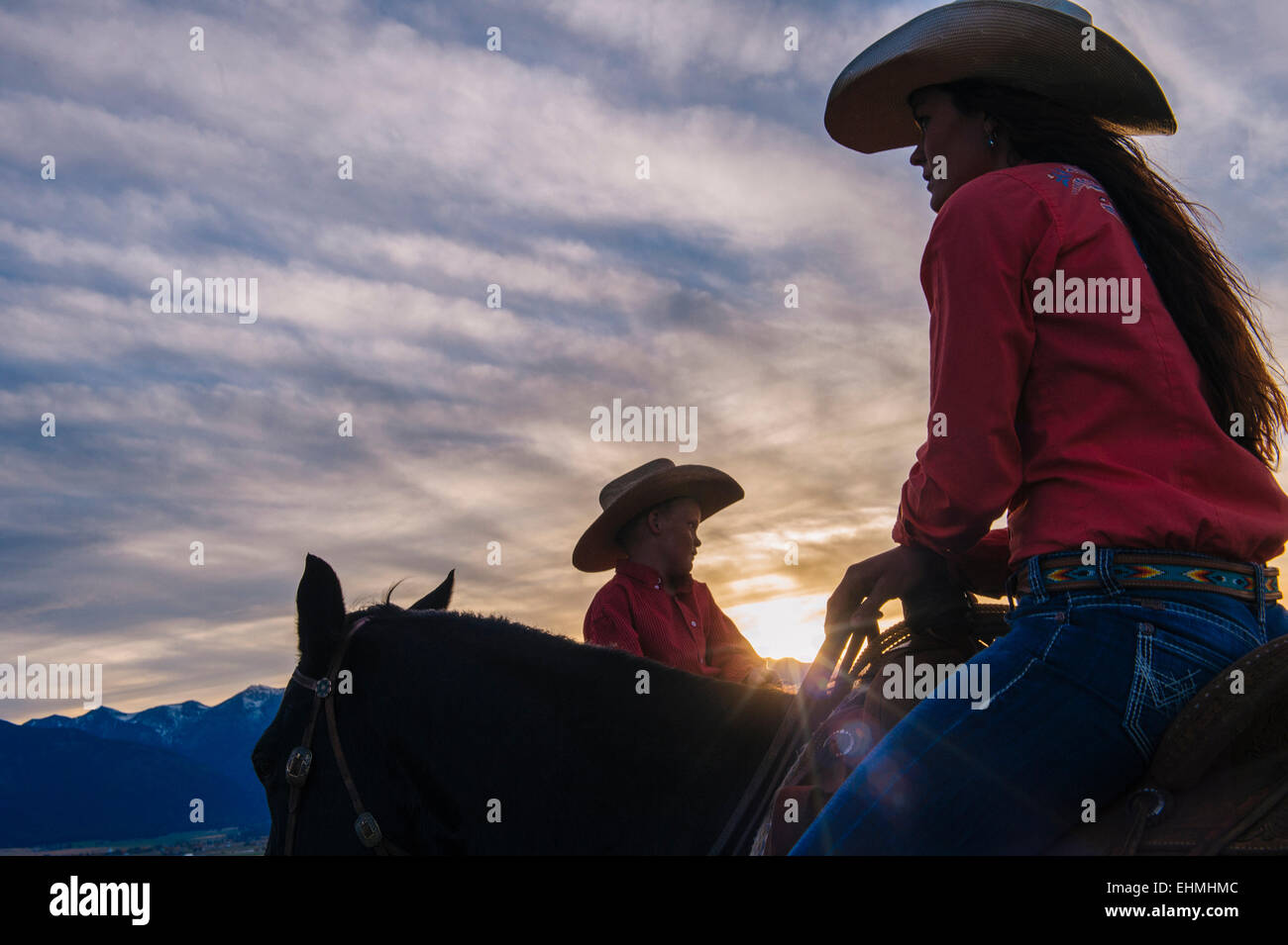 Caucasian mother and son riding horses at sunset Banque D'Images