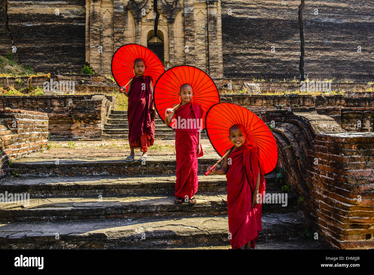 Les moines d'Asie sous les parasols debout près de temple historique, Mingun, Mandala, Myanmar Banque D'Images