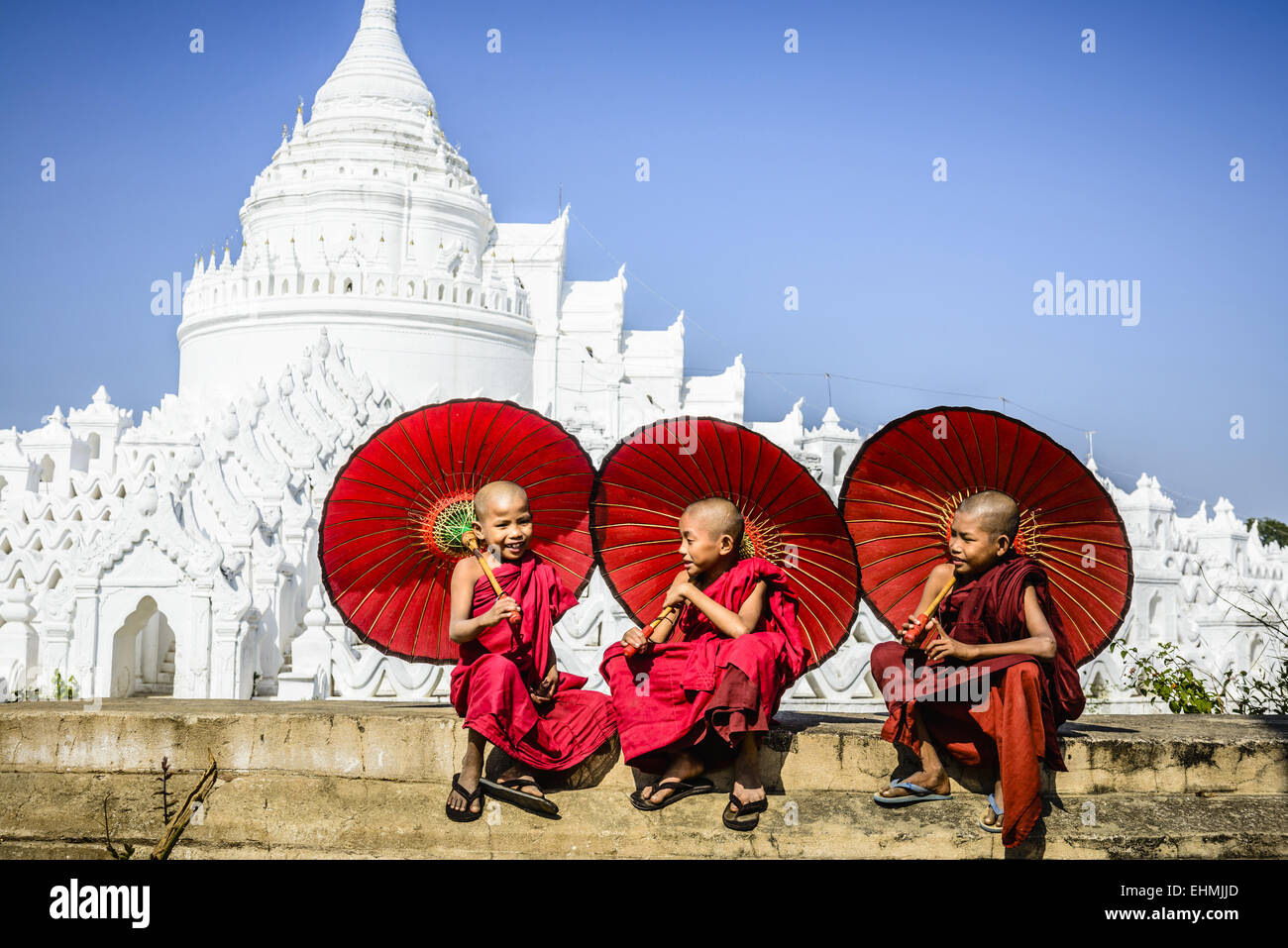 Les moines asiatiques assis sous les parasols près de temple historique, Mingun, Mandala, Myanmar Banque D'Images