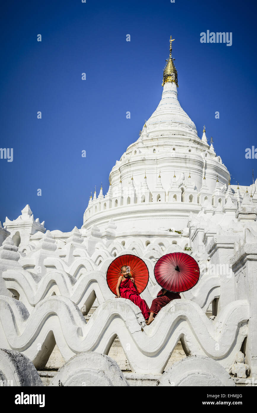 Les moines asiatiques assis sous les parasols au temple historique, Mingun, Mandala, Myanmar Banque D'Images
