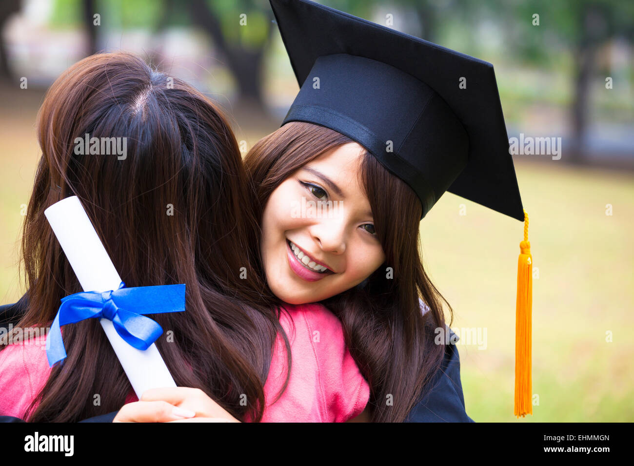 Les jeunes diplômés de sexe féminin hugging her friend à cérémonie de remise de diplômes Banque D'Images